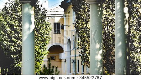 White Doric Columns On The Background Of A Cozy House