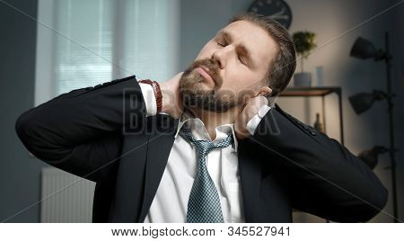 Tired Office Worker Sitting With Closed Eyes Tilted Head And Massaging His Crick In The Neck With Bo