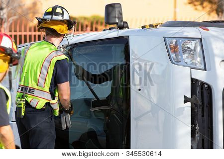 Emergency Responders Cracking The Window Of A Mini Van At Accident Site