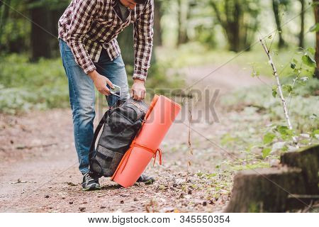Hiker Holding His Camping Backpack. Traveler Opening Backpack While Traveling In Beautiful Wood. The
