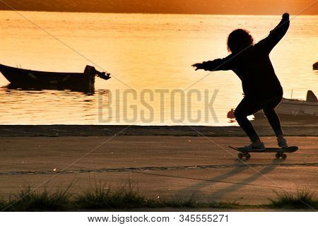 Oporto, Portugal- January 1, 2020: Young Boy Skating At Sunset On The Banks Of The Douro River In Op