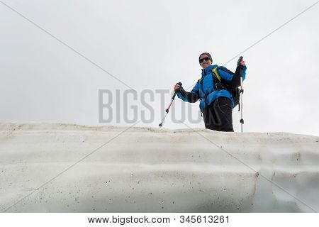 Female Mountaineer Standing On Top Of Melting Snow Ridge.