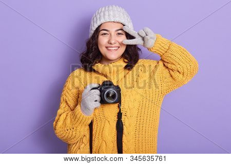 Studio Shot Of Attractive Brunette Female Holding Her Camera In Hands Composing Photograph In Studio