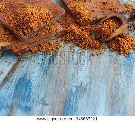 Brown Unrefined Cane Sugar On A Blue Wooden Table Close Up