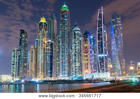 Dubai Skyline At Night With Lights On The Water And Luxirious Skyscrapers Of Uae. Modern Architectur