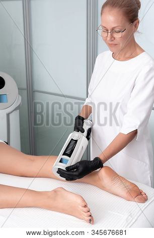 Cosmetologist In Rubber Gloves Doing Endospheres Therapy On Female Legs