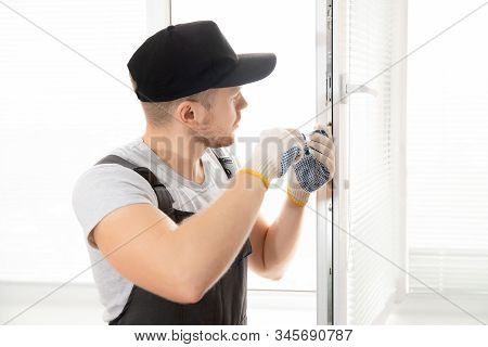Construction Worker Man Uses Screwdriver To Screw Handle Install Plastic White Upvc Windows In House
