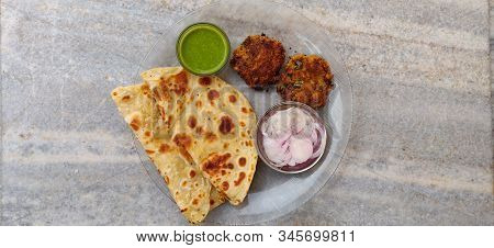 Hydrabadi Kawab Paratha With Green Chili Sauce & Onion On Transparent Plate. Kabab An Irani Dish Wit