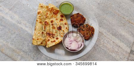 Hydrabadi Kawab Paratha With Green Chili Sauce & Onion On Transparent Plate. Kabab An Irani Dish Wit