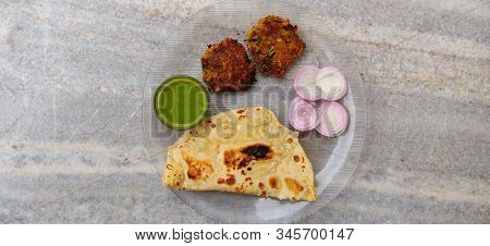 Hydrabadi Kawab Paratha With Green Chili Sauce & Onion On Transparent Plate. Kabab An Irani Dish Wit