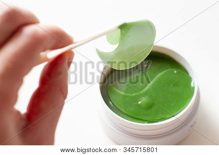 Young Woman With Tweezers Holds Eye Masks Patches.
