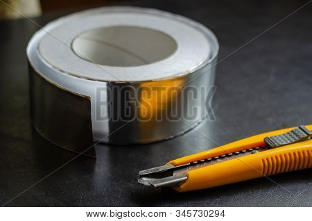 Used Knife In The Foreground. Reel With Tape For Thermal Insulation In The Background. Eye Level Sho