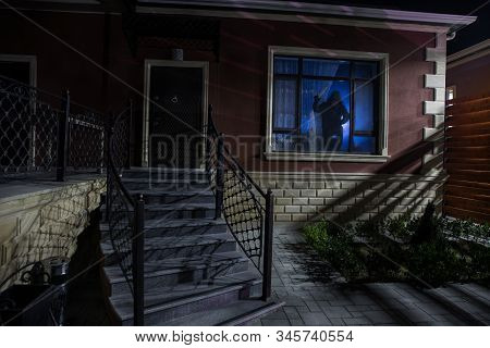 Old House With A Ghost In The Forest At Night. Horror Silhouette At The Window. Old Building In Fore