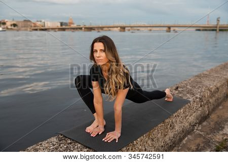 Yoga Meditation And Wellness Lifestyle Concept. Fit Slim Woman Practicing Yoga Exercises Near River 