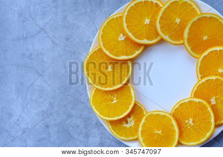 Orange Juicy Sliced Orange On A White Round Plate On A Concrete Blue Background Copyspace