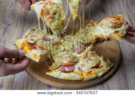 People Are Snatching Pieces Of Pizza With Mozzarella. Salami And Tomatoes. Top Views