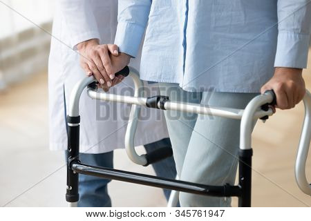 Close Up Nurse Holding Disabled Older Woman Hand On Walker
