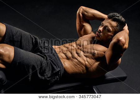Close Up Of Muscular Shirtless Man Training Abs On Mat In Gym. From Above View Of Handsome Young Spo