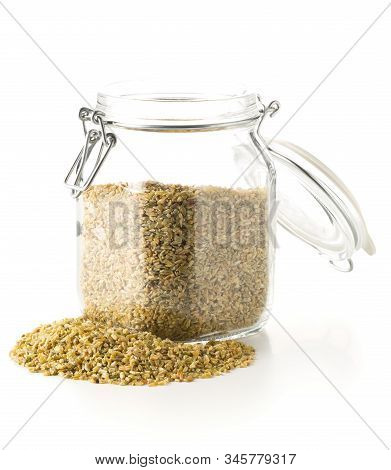 Heap Of Uncooked, Raw Freekeh Or Firik, Roasted Wheat Grain, In Glass Storage Jar Over White Backgro