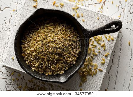 Uncooked, Raw Freekeh Or Firik, Roasted Wheat Grain, In Metal Pan On White Rustic Table Background T