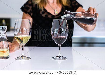 Female Bartender Hand Close Up As She Pouring Red Wine From A Small Mini Decanter To The Wineglass, 
