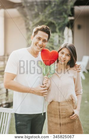 Romantic Happy Asian Couple In Love Holding Heart Shape Flower. Vanlentine Day Concept.