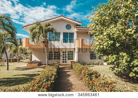 Beautiful Landscape Design In Front Of A Two-story Mansion. Palm Trees Grow In The Garden. A Hedge O