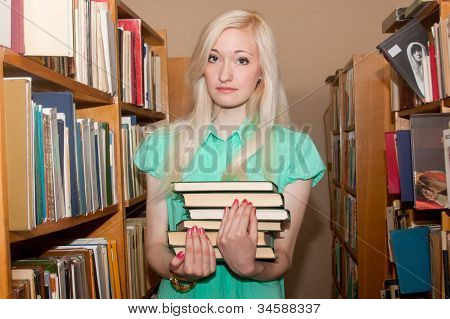 Mujer joven con libros en la biblioteca