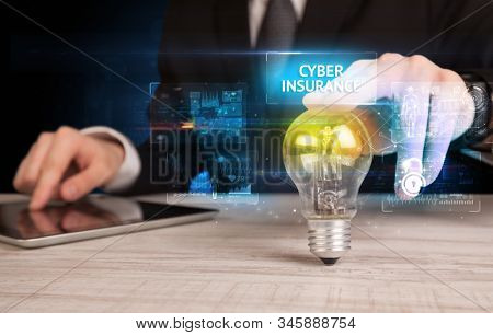 Businessman holding lightbulb with CYBER INSURANCE inscription, online security idea concept