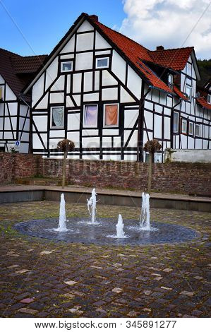 Bodenwerder, Germany - April 20, 2016: Half-timbered house and fountain in Bodenwerder, Lower Saxony, Germany.                                    