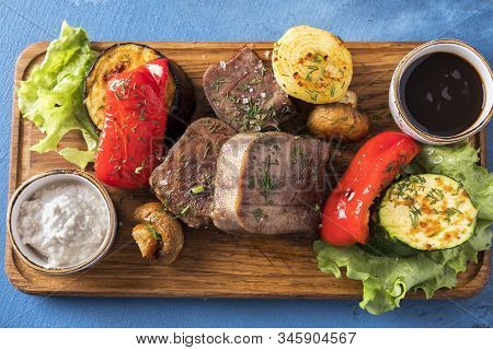 Beef Tongue On A Grill With Vegetables Served With Demiglas Sauce And Horse-radish. Top View
