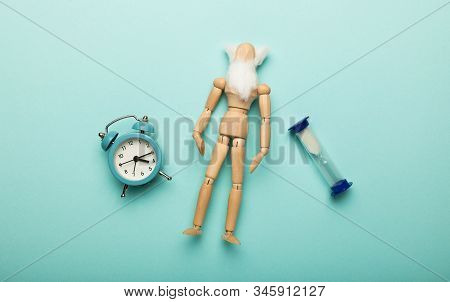 Сoncept Of Aging And Old Age (senescence). Miniature Wooden Man With Clock. Longevity Of Population.