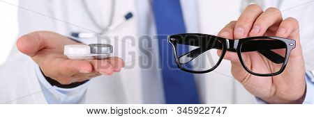 Male Doctor Hands Giving Pair Of Black Glasses And Contact Lens To Patient Offering Choice. Eyesight