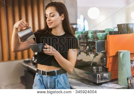 Young Smiling Barista Woman Pouring Whipped Milk Into Coffee Drink, Preparing Latte Macchiato