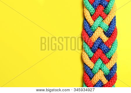 Top View Of Braided Colorful Ropes On Yellow Background, Space For Text. Unity Concept