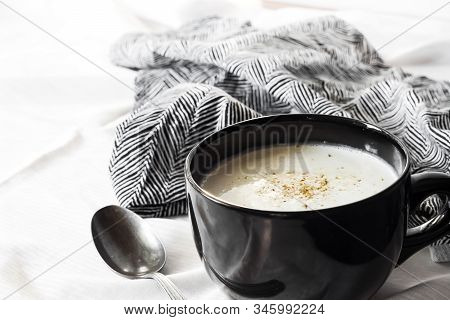 Cauliflower Soup (creme Du Barry) In Black Bowl On White Background With Black And White Cloth.