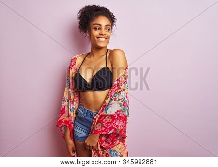 Young beautiful african american woman on vacation standing wearing bikini and colorful caftan