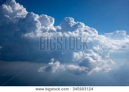 Huge white clousds on a background of blue sky lighted bright sunny beams with copy space for text. Travel and tourism concept.