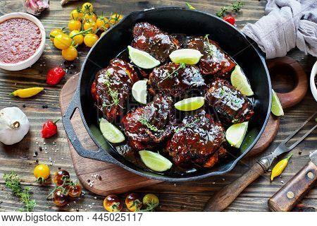 Top View Of A Spicy Chili Chicken Thigh Meat In A Cast Iron Pan Over A Wooden Cutting Board And Rust
