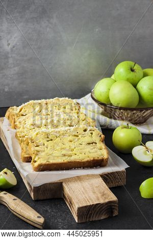 Sliced Apple And Coconut Oaf Cake On Wooden Cutting Board On Dark Background