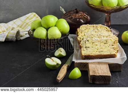 Sliced Apple And Coconut Oaf Cake On Wooden Cutting Board On Dark Background