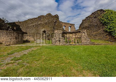 Outdoor Ruins Of The Medieval Castle Of Bourscheid, Outer Esplanade With Weathered Stone Walls In Th