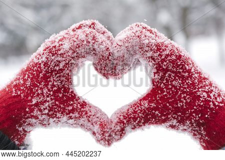 Woman Making Heart Symbol With Snowy Hands