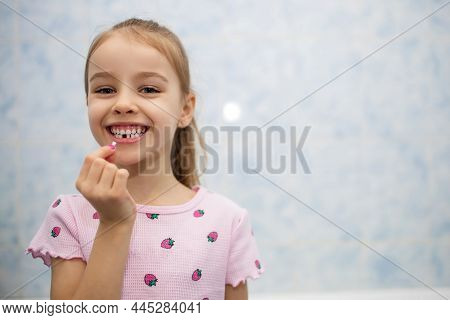 Girl Child Shows Her Mouth Without One Lost Milk Tooth And Smiles. A Child In The Bathroom Holds A M