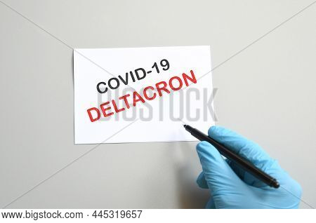 Doctor's Hand In Blue Glove With White Paper And Text Deltacron. Concept Of Medical Variety Deltacro