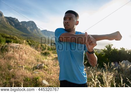 Black Young Adult Male Stretching, Preparing For His Morning Run On The Mountain