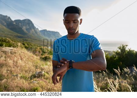 Black Young Adult Male Checking His Sports Watch While On An Outdoor Run In The Mountain