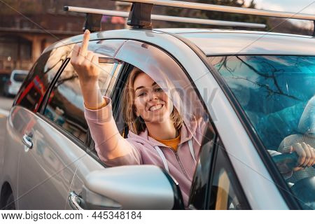Porrait Of Young Smiling Woman Is Sitting Behind The Wheel Of Right-hand Drive A Car And Shows Her M