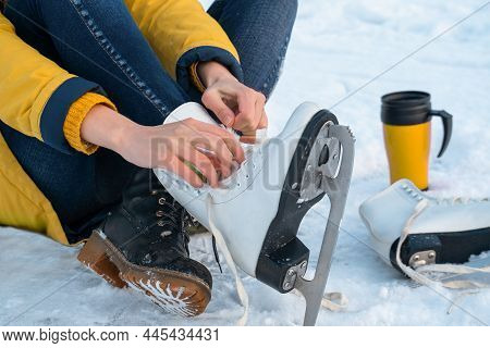 Young Woman Putting On Ice Skates. Female Hands Tying Laces. Close Up