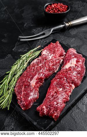 Raw Machete Steak Or Hanging Tender Cut With Herbs. Black Background. Top View